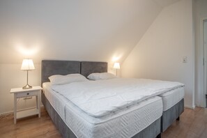 Ett sovrum med en säng, två sänglampor, ett nattduksbord och en dörr.