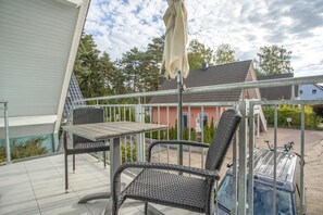 An outdoor patio with a table and chairs, a covered umbrella, and a view of a residential area. - Apartment 'Haus K 102 OG' with Private Garden, Balcony and Wi-Fi (Röbel)