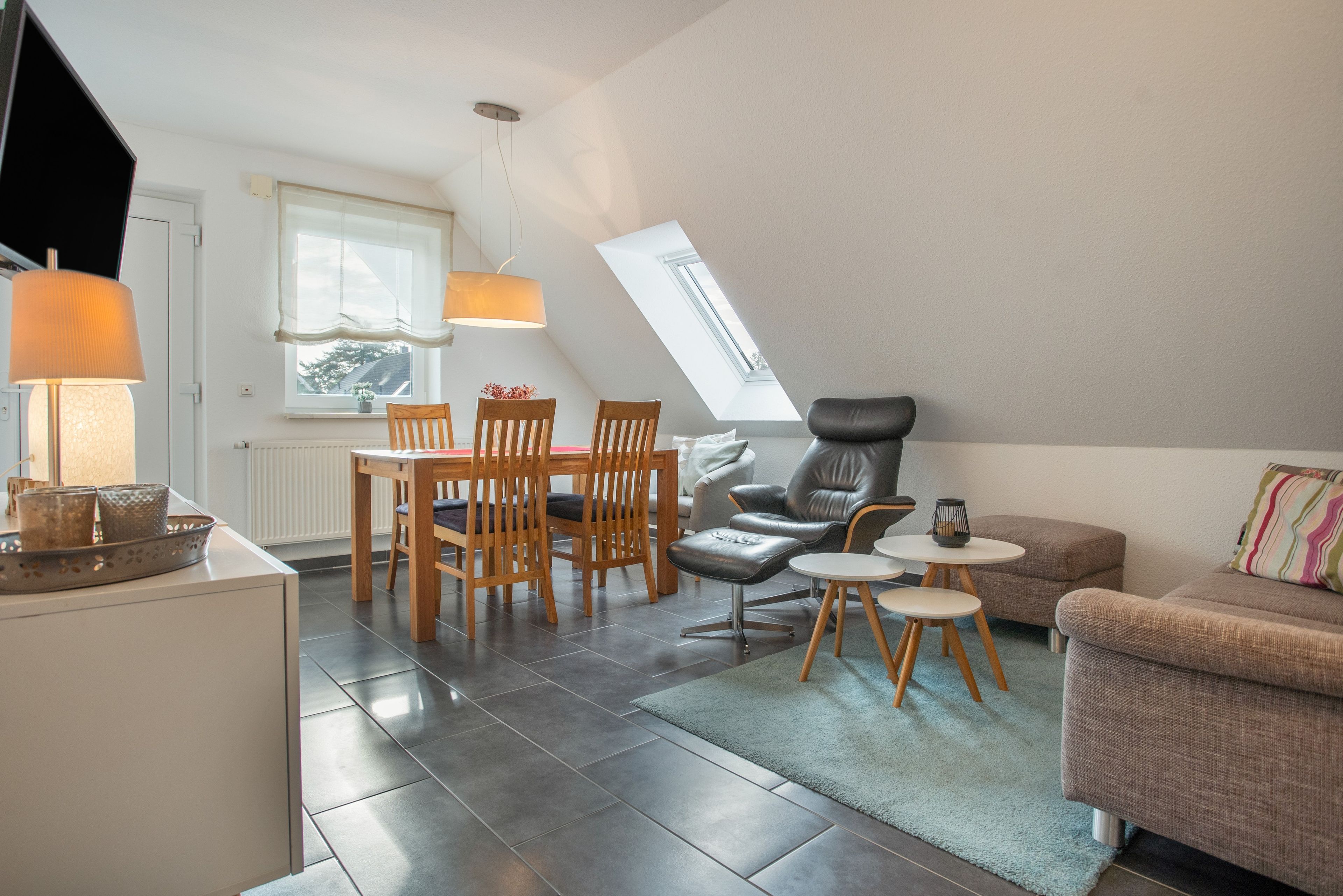 Moderni loft-tyylinen huoneisto, jossa on ruokailutila, oleskelualue sohvineen ja tuoleineen sekä suuri kattovalokuvio.