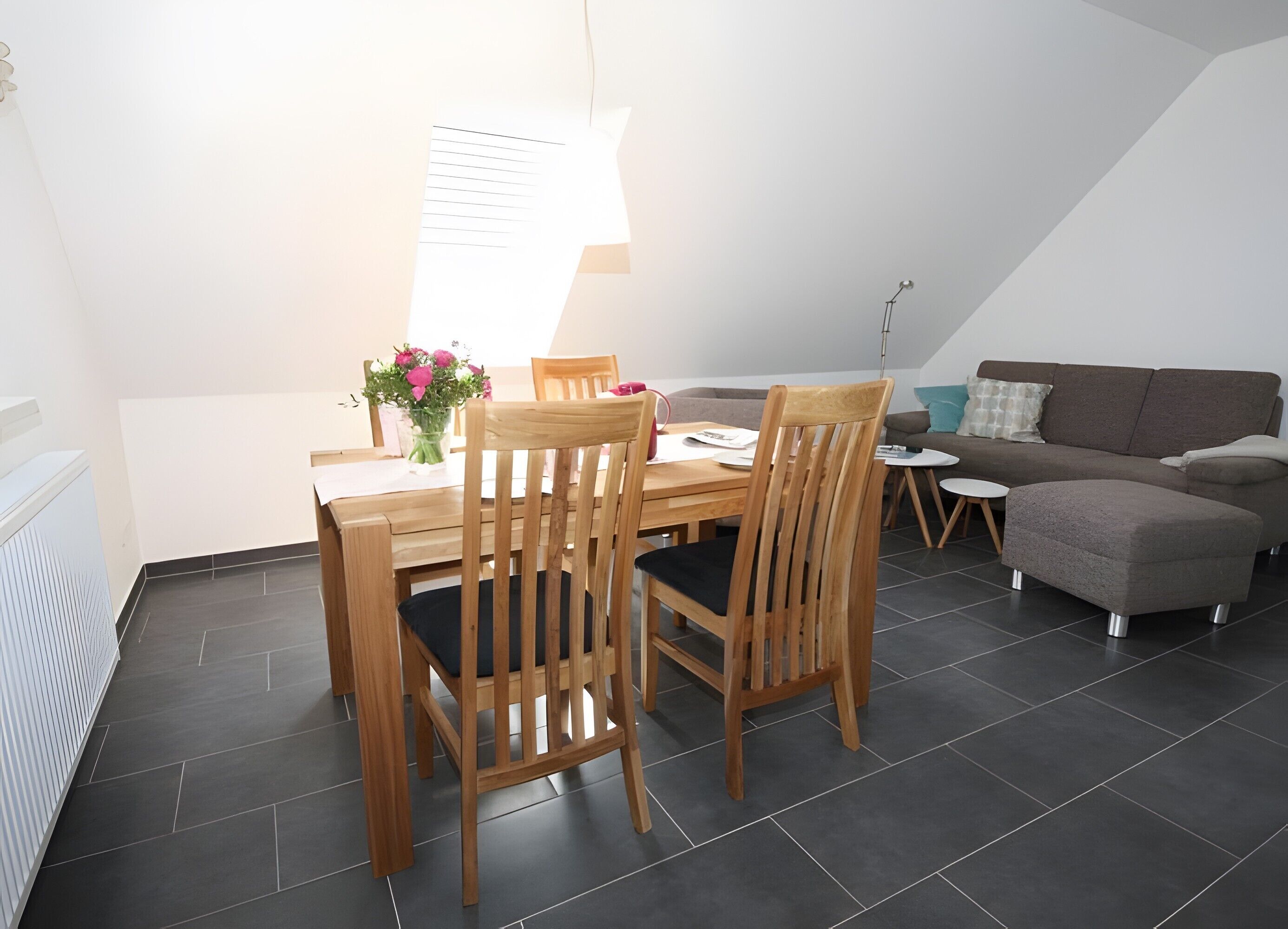 Un coin repas avec une table, des chaises et un vase de fleurs.