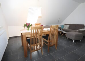 Een eethoek met een tafel, stoelen en een bloevas.