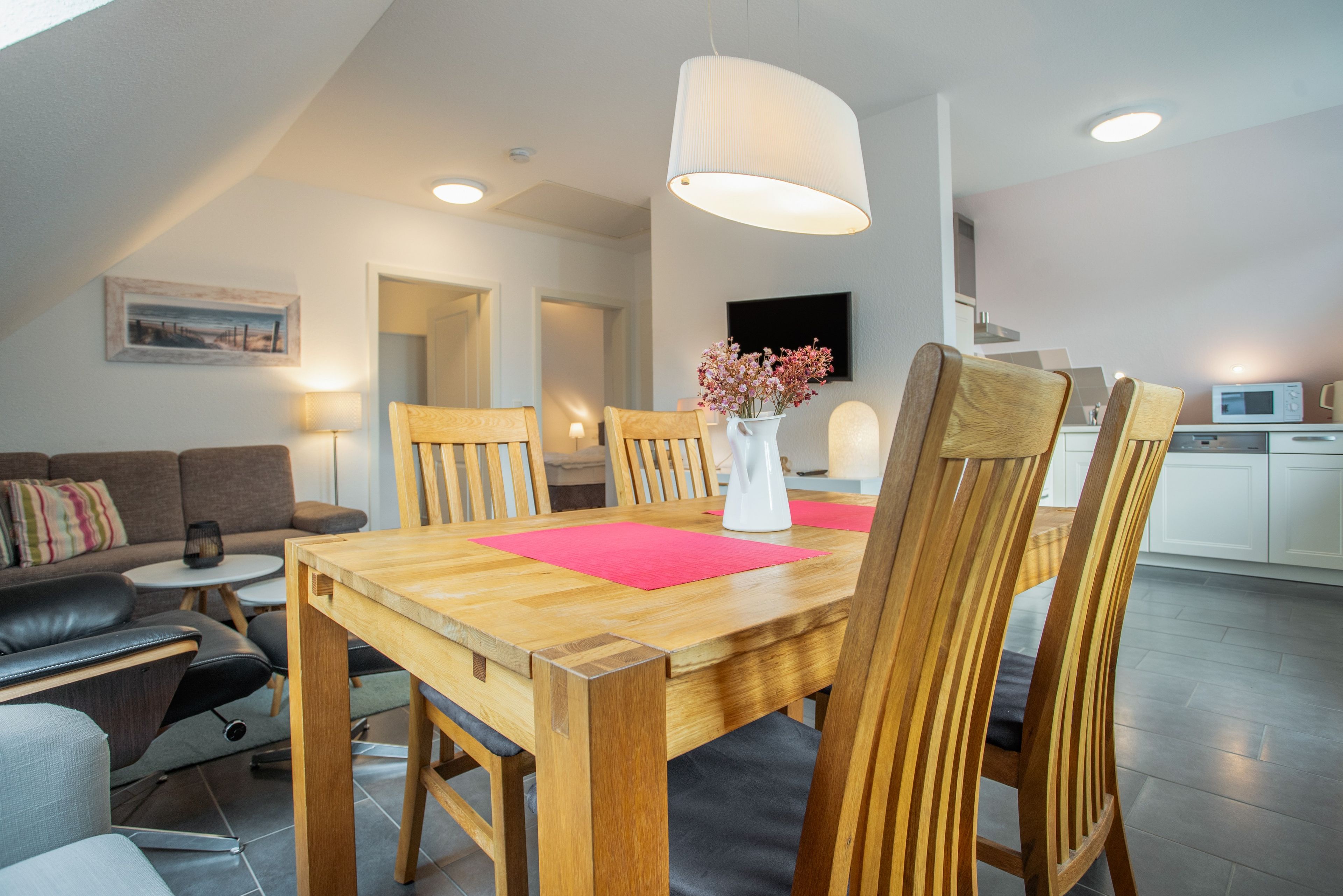 Un espace de vie moderne comprenant une table à manger, des chaises, un canapé, une table basse et un coin cuisine.
