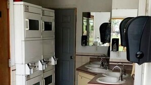 A compact kitchen with a microwave, stove, sink, and a trash bin. - Spacious Cabin with Heated Pool Near Black Hills in Sturgis, South Dakota (Sturgis)