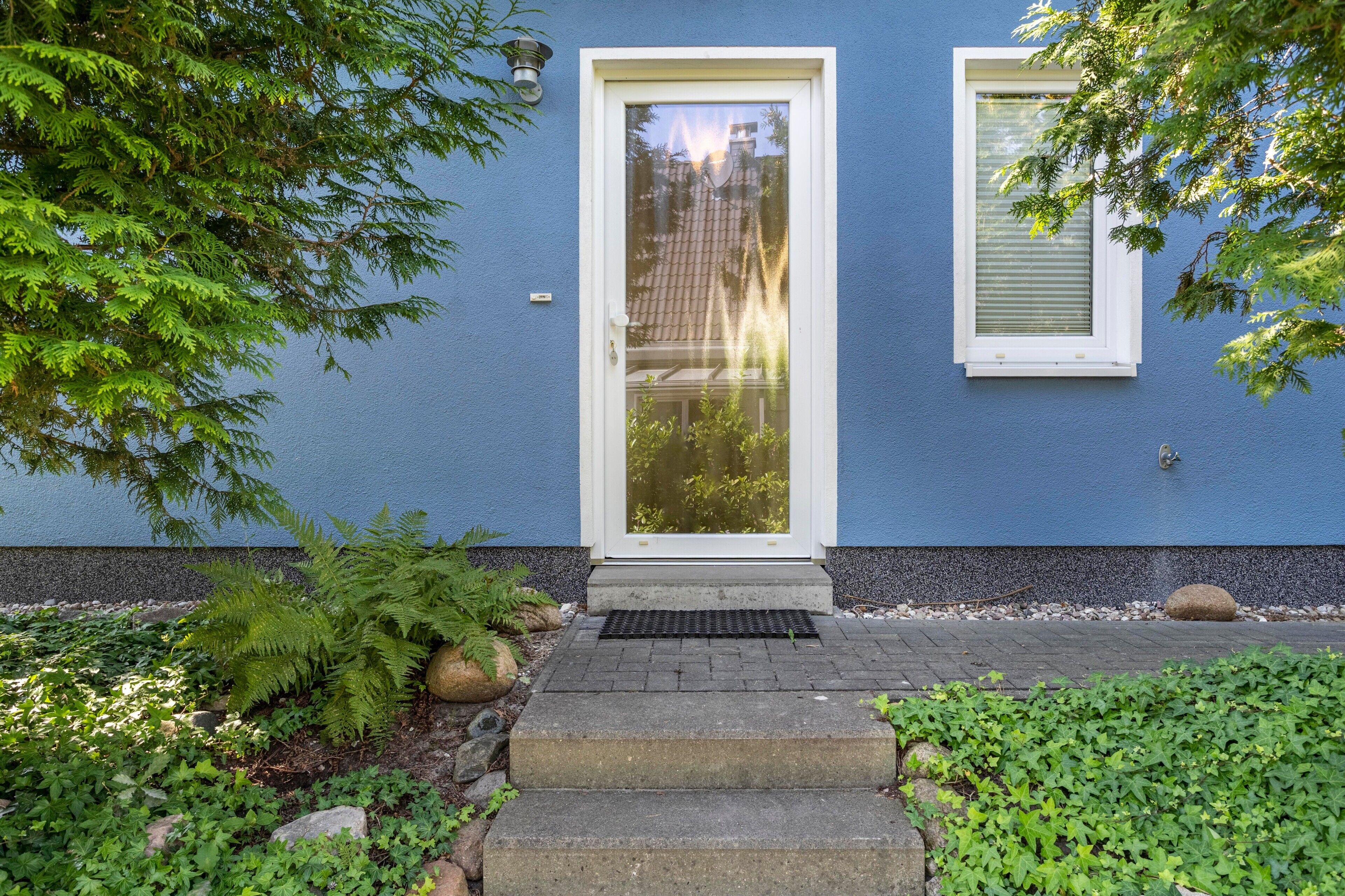 A house with a blue exterior, a white door, and a window with shutters.