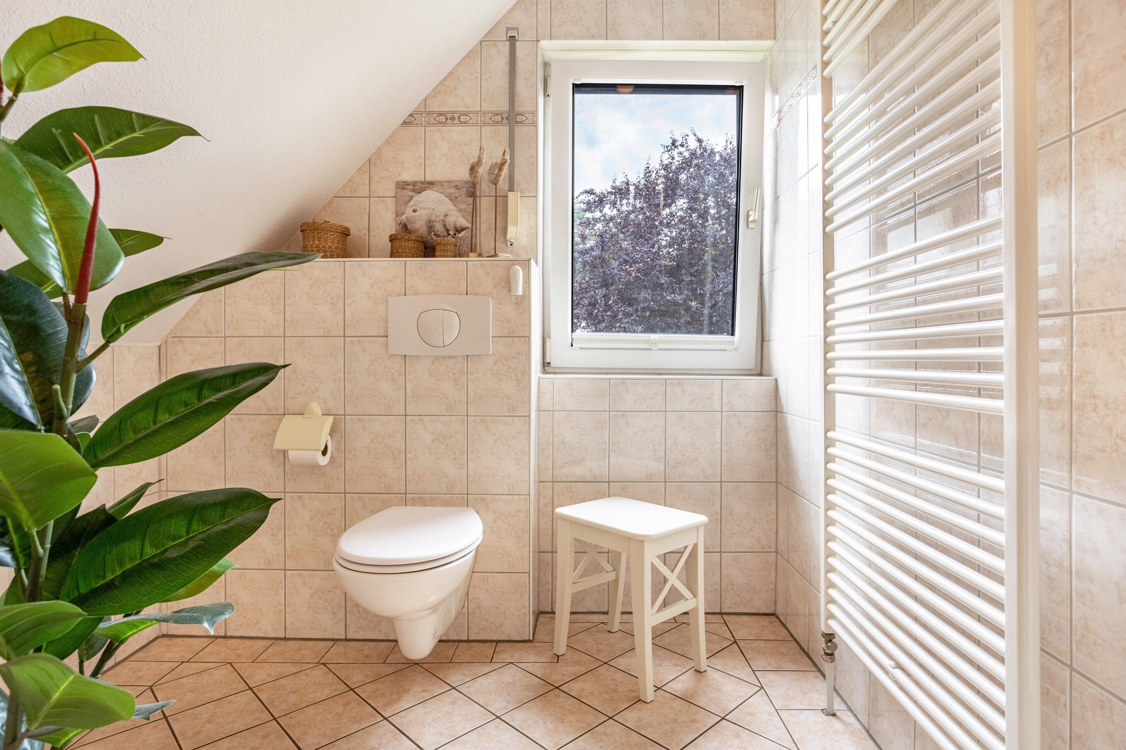 Et lille badeværelse med toilet, et vindue og en radiator.