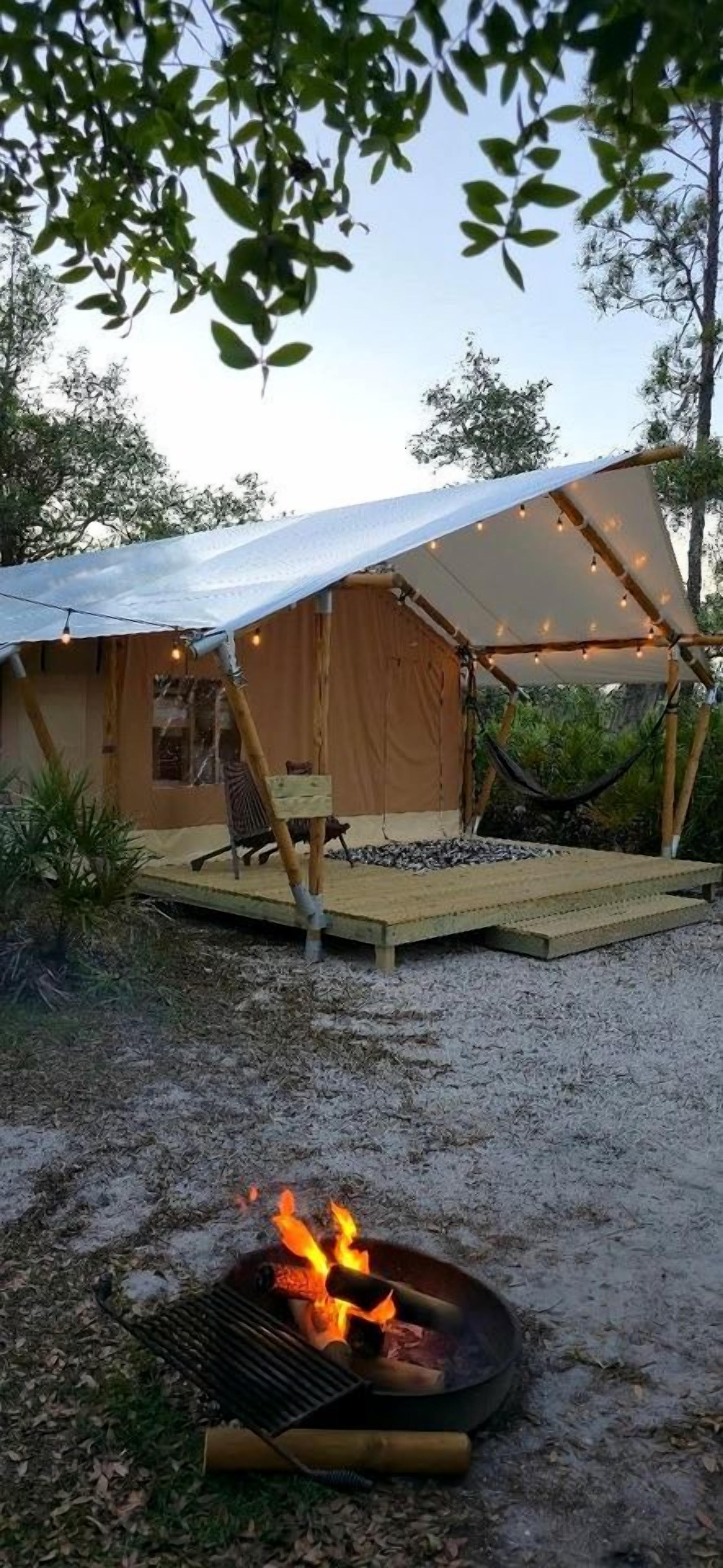 A tented accommodation with a fire pit and a deck.