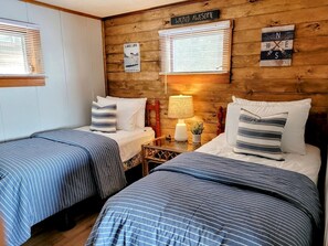 A room with two beds, wooden walls, a sign reading 'WICKED AWESOME,' and a 'LAKE LIFE' poster. - Scenic Lakeside Cabin with Exclusive Boat Dock Near Weirs Beach, Laconia, New Hampshire (Laconia)