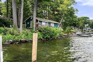 Una casa junto a un río tranquilo con barcos amarrados.