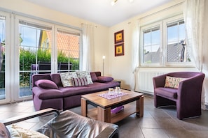 A living room with a purple sofa, a wooden coffee table, and a purple armchair. - Apartment 'Haus 28 EG' with Private Terrace, Private Garden and Wi-Fi (Röbel)