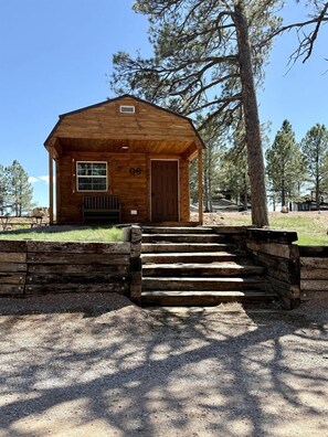 A wooden cabin with a front door, a window, and a set of steps leading up to it. - Charming Cabin with Barbecue and Great Sights in Rapid City, South Dakota (Rapid City)