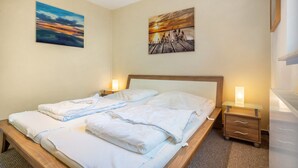 A hotel room with a bed, bedside tables, and wall art.