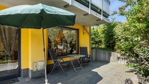 An outdoor seating area with a table and chairs, a patio umbrella, and a scooter.