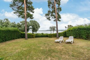A grassy outdoor area with two white lounge chairs and a view of a body of water. - Apartment 'Haus 7 EG' with Lake View, Private Terrace and Wi-Fi (Röbel)