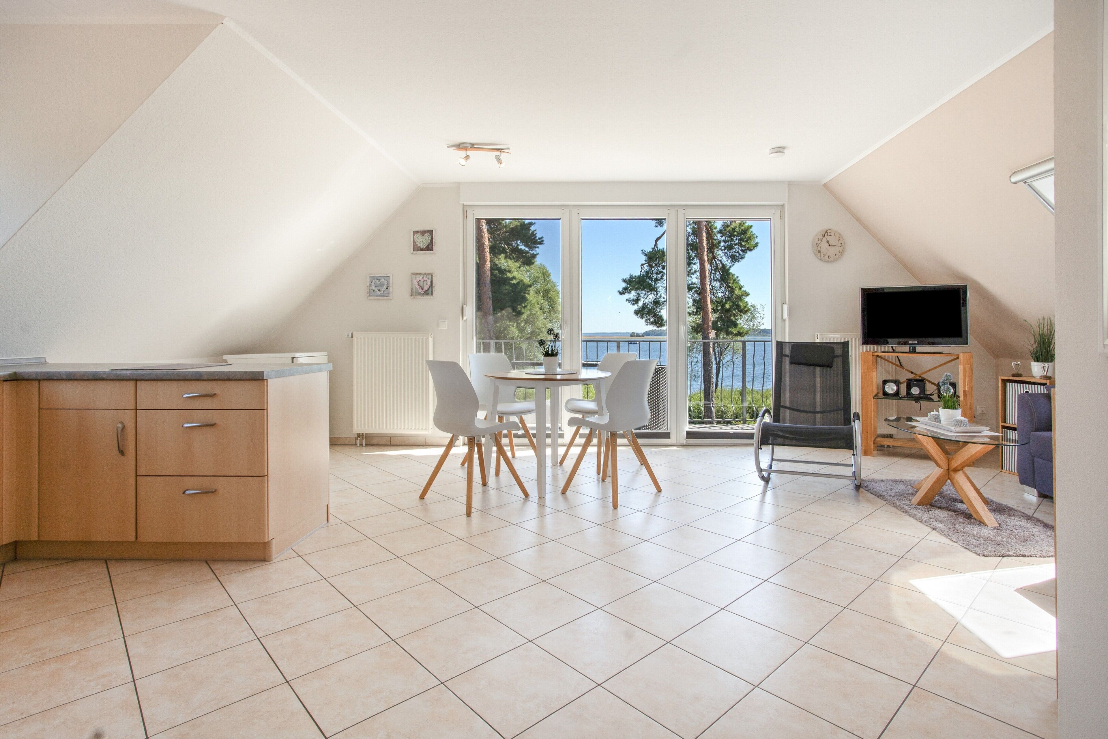 A spacious living area with a dining table, chairs, a television, and a view of the outdoors.