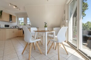 A modern kitchen with white cabinets, a microwave, and a dining area with a round table and four chairs. - Apartment 'Haus 7 OG' with Lake View, Private Garden and Wi-Fi (Röbel)