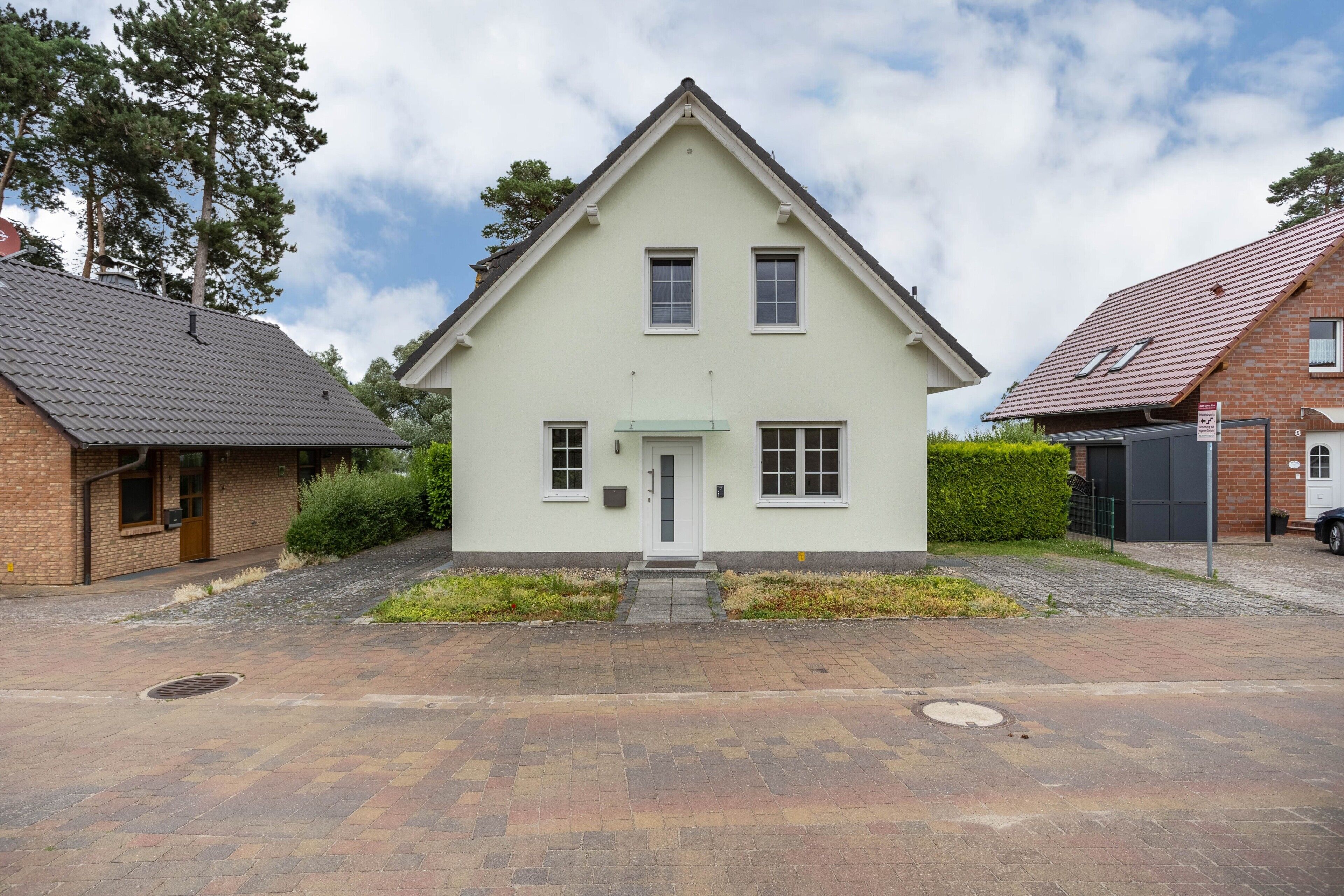A two-story house with a symmetrical facade, a central entrance with a small porch, and a paved driveway.