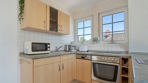 A kitchen with wooden cabinets, a microwave, a Bosch dishwasher, and an oven. - Apartment 'Haus 7 OG' with Lake View, Private Garden and Wi-Fi (Röbel)