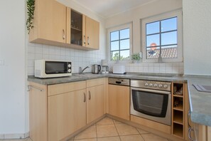 A kitchen with wooden cabinets, a microwave, a Bosch dishwasher, and an oven. - Apartment 'Haus 7 OG' with Lake View, Private Garden and Wi-Fi (Röbel)