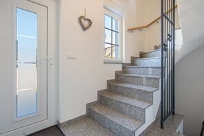 A staircase with granite steps leading to a landing, a white door with a glass panel, and a small window with a view of a house. - Apartment 'Haus 7 OG' with Lake View, Private Garden and Wi-Fi (Röbel)