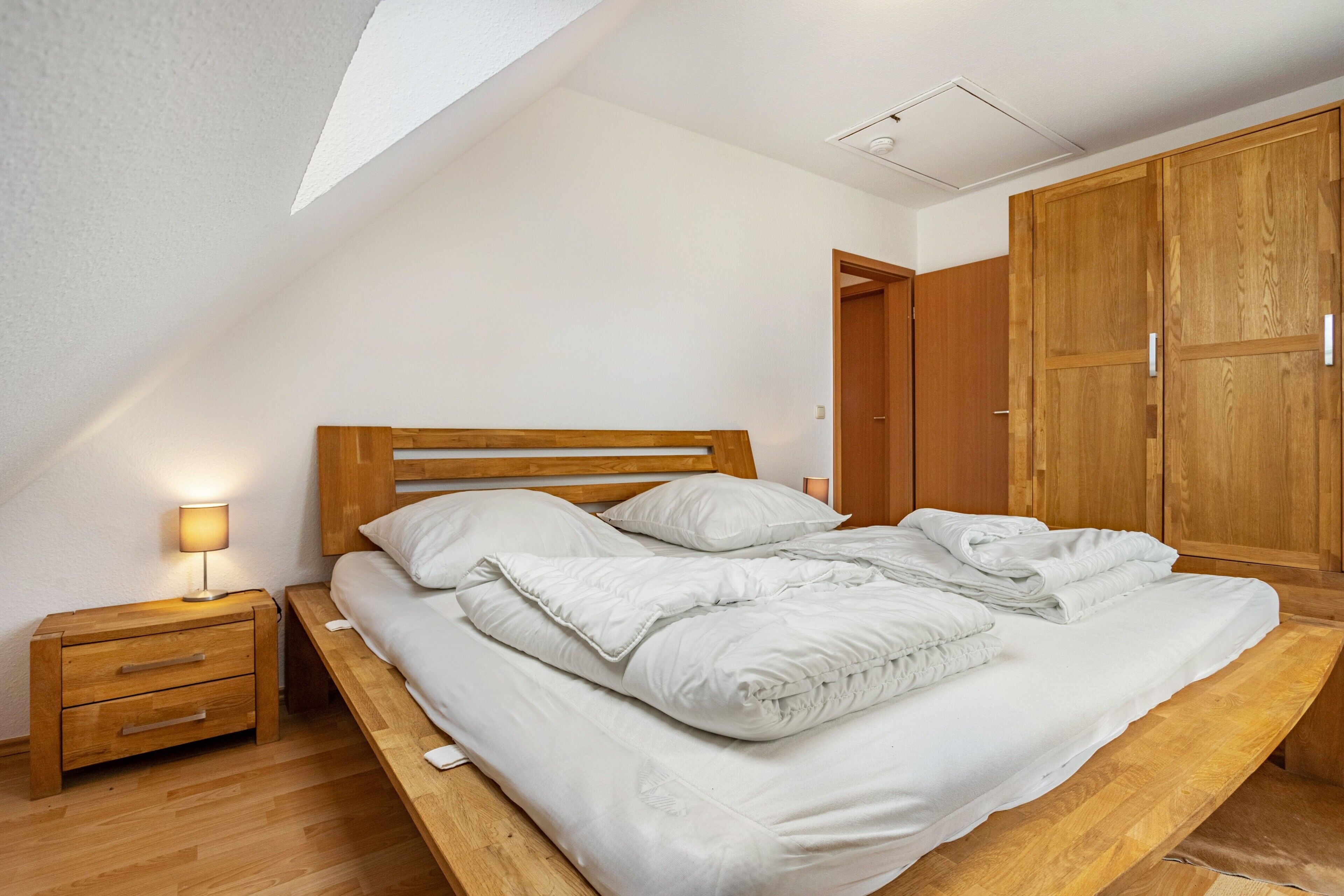 Een slaapkamer met een houten bed, nachtkastje en een kledingkast.