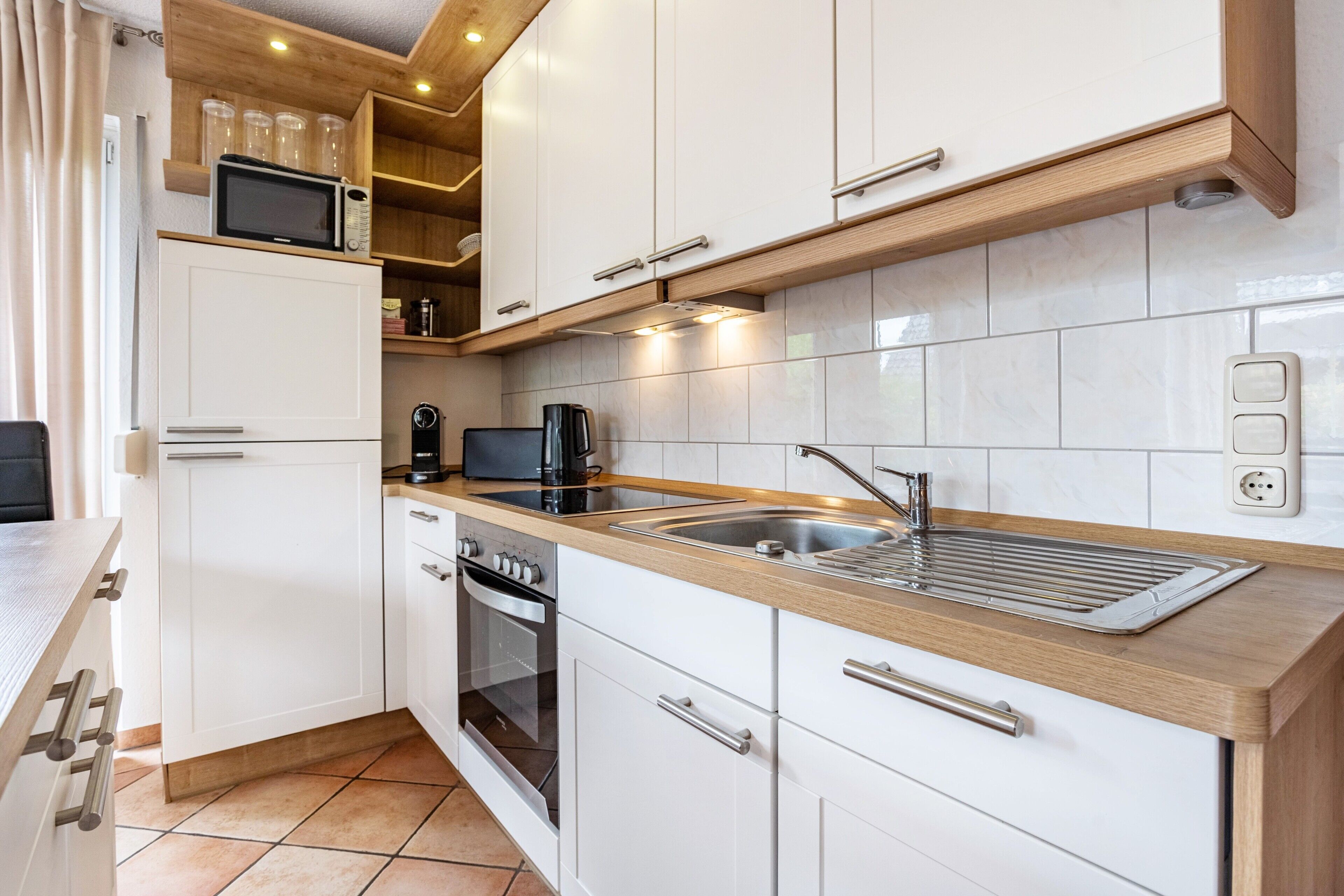 Een moderne keuken met witte kastjes, een roestvrijstalen spoelbak en een inbouwoven.
