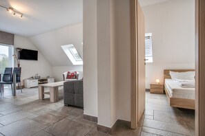 A modern bedroom with a sloped ceiling, a bed, a bedside table, and a desk with a chair. - Apartment 'Haus U13 OG' with Private Terrace, Private Garden and Wi-Fi (Röbel)
