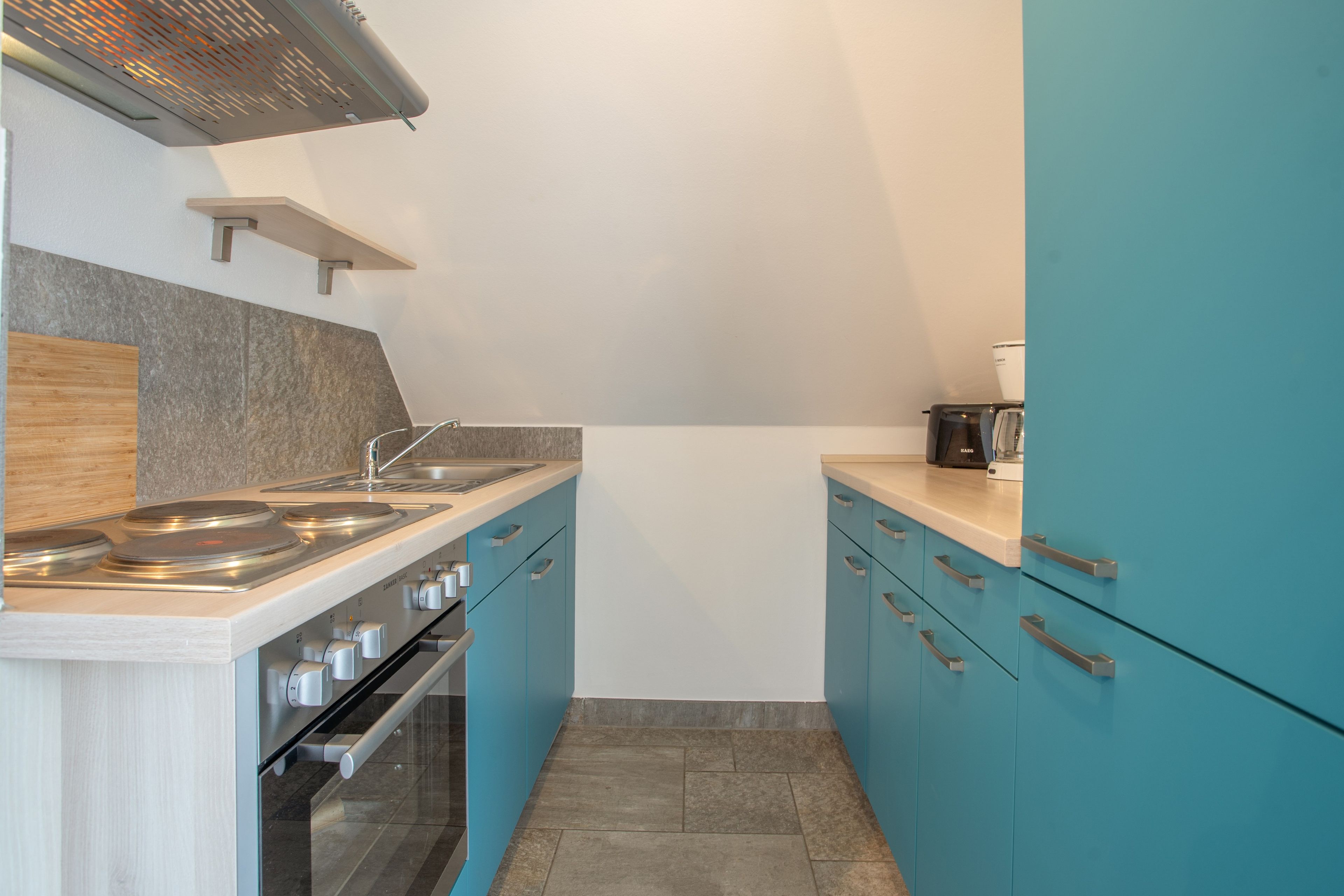 Una cocina con estufa a gas, horno y cafetera en la encimera.