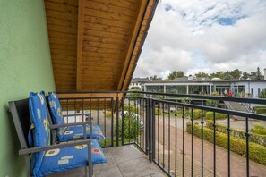 A balcony with a wooden ceiling, a metal railing, and blue cushions with sunflower patterns. - Apartment 'Haus U13 OG' with Private Terrace, Private Garden and Wi-Fi (Röbel)