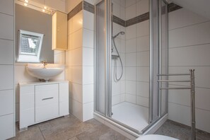 A modern bathroom with a glass-enclosed shower, a white sink, and a cabinet with drawers. - Apartment 'Haus U13 OG' with Private Terrace, Private Garden and Wi-Fi (Röbel)