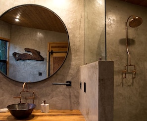 A bathroom with a round mirror, wooden sink, and a shower with a curved design.