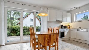 Uma cozinha moderna com uma mesa de jantar e cadeiras, forno embutido e uma janela grande.