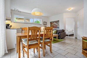 A modern kitchen with a dining area, a sofa, and a painting on the wall. - Apartment 'Haus 44 EG' with Lake View, Private Terrace and Wi-Fi (Röbel)