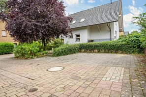 Un pati pavimentat amb un arbre, una altra tanca i un edifici amb teulada.
