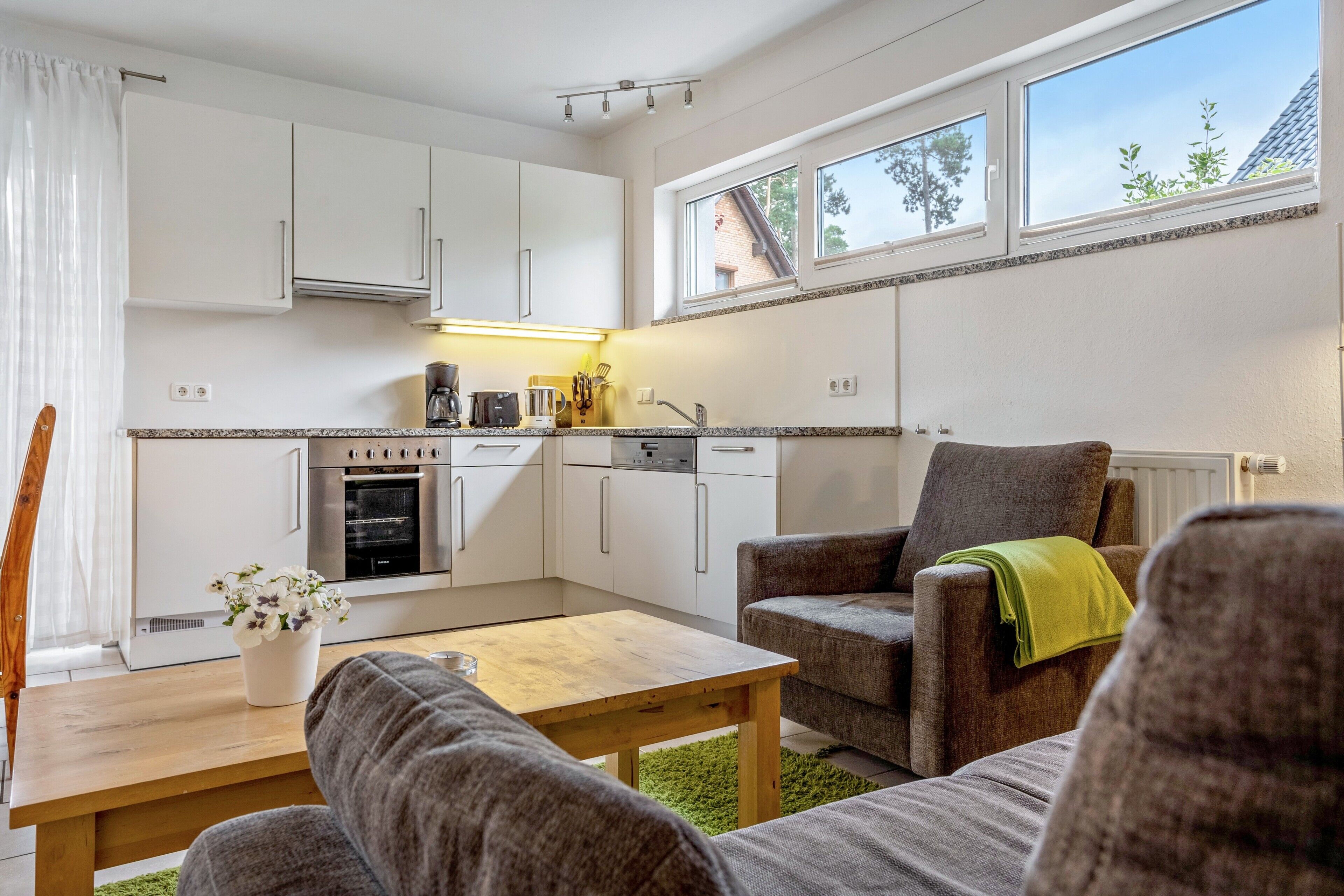 A compact living space with a kitchenette, a dining area, and a seating area with a view of the outdoors.