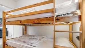 Uma cama de solteiro com estrutura de madeira, um colchão e um cobertor dobrado na cama inferior.