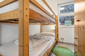 A bunk bed room with a green mat, wooden wardrobe, and a window with a view of trees. - Apartment 'Haus 44 EG' with Lake View, Private Terrace and Wi-Fi (Röbel)