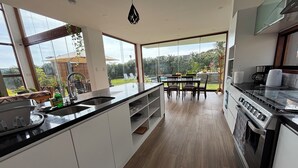 A modern kitchen with a large island, a dining area with chairs, and a view of the outdoors.