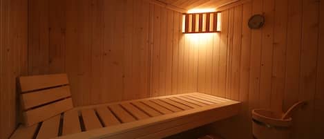 A wooden sauna with benches and a bucket.