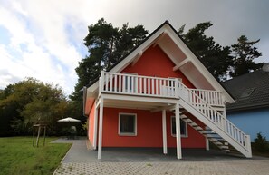 Un edifici vermell amb un balcó blanc i una escala.
