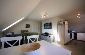 Eine moderne Küche mit Essbereich, einem über der Arbeitsplatte montierten Fernseher und einem Deckenventilator.