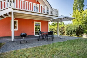 Ein rotes Gebäude mit Balkon, Grill und Gartenmöbeln.
