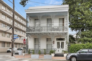 Ein zweistöckiges Gebäude mit schmiedeeisernen Balkonen, einer weißen Fassade und der Hausnummer 1141 am Eingang.