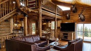 A log cabin interior with a leather sofa, wooden dining table, and a mounted television. - Fabulous 5-bedroom cabin in Westcliffe perfect for your getaway (Westcliffe)