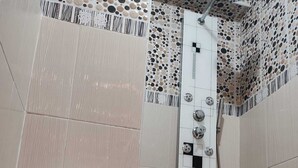 Un bagno con il water, una doccia e un pannello di controllo a parete.