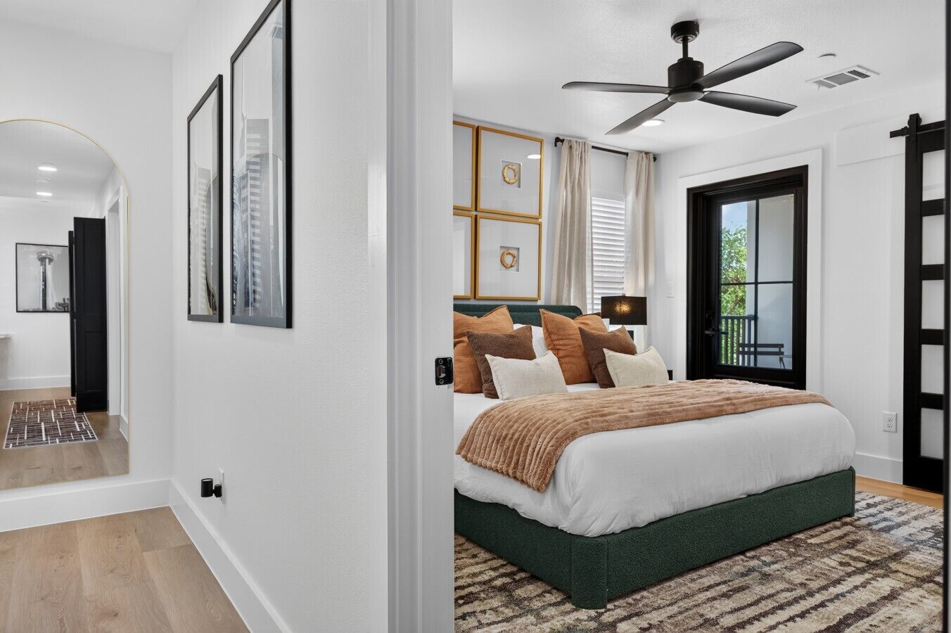 A modern bedroom with a large bed, a ceiling fan, and a view of the outdoors.