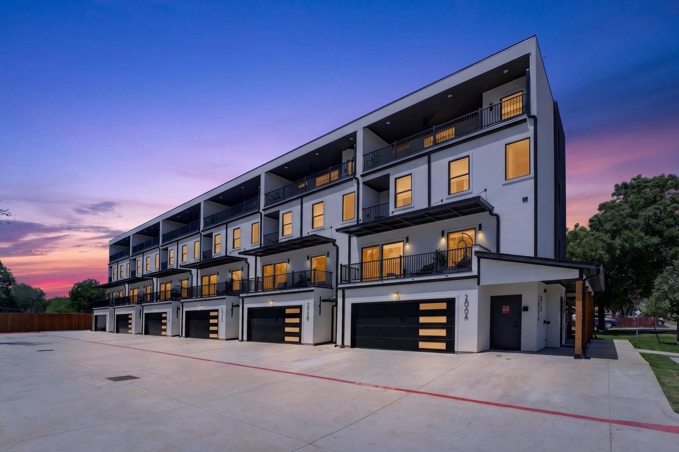 A multi-story residential building with balconies, large windows, and garage doors.