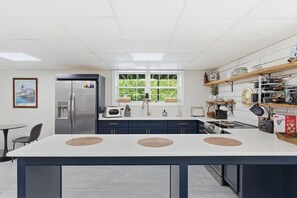 A modern kitchen with a central island, stainless steel appliances, and a large window.