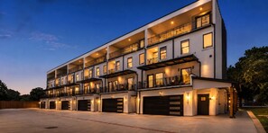 A multi-story residential building with balconies, large windows, and garage doors. - Luxury Townhome D. Walk to AT&T Stadium. Rooftop Terrace + Game Room. Sleeps 10. (Arlington)