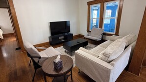 Una sala de estar con un sofá, sillones, una mesa de centro, un televisor y un ventanal con vistas.
