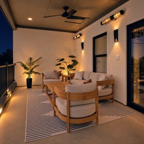 An outdoor seating area with a ceiling fan, two potted plants, and a wooden table and chairs. - Luxury Townhome A. Walk to AT&T Stadium. Rooftop Terrace + Game Room. Sleeps 10. (Arlington)